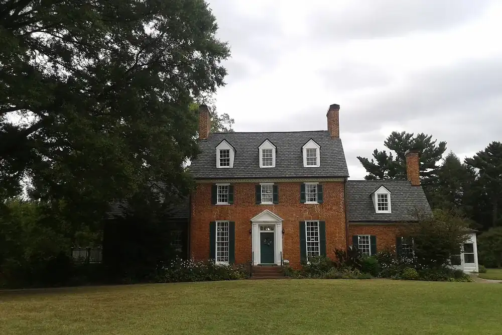 Historic brick manor house with dormer windows and a wide lawn at Green Spring in Annandale, Virginia