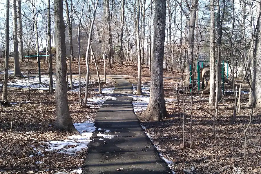 Paved wooded walking path past a playground in Burke Centre, Virginia