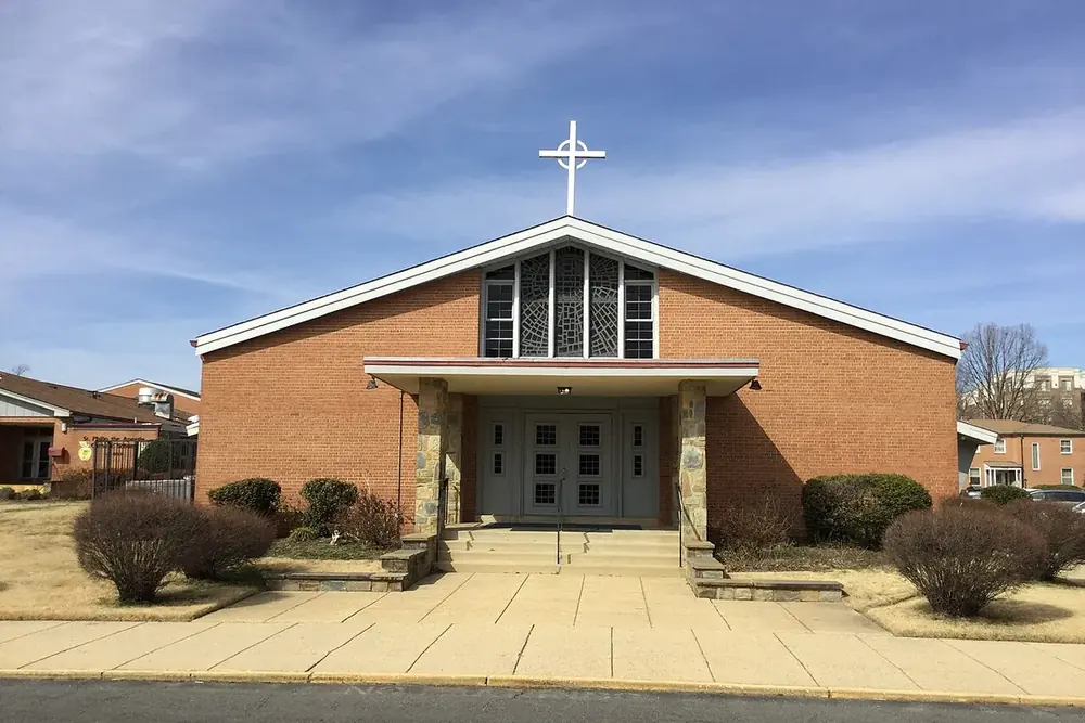 Brick St. Philip church with a white cross under a clear sky in Camp Springs, Maryland
