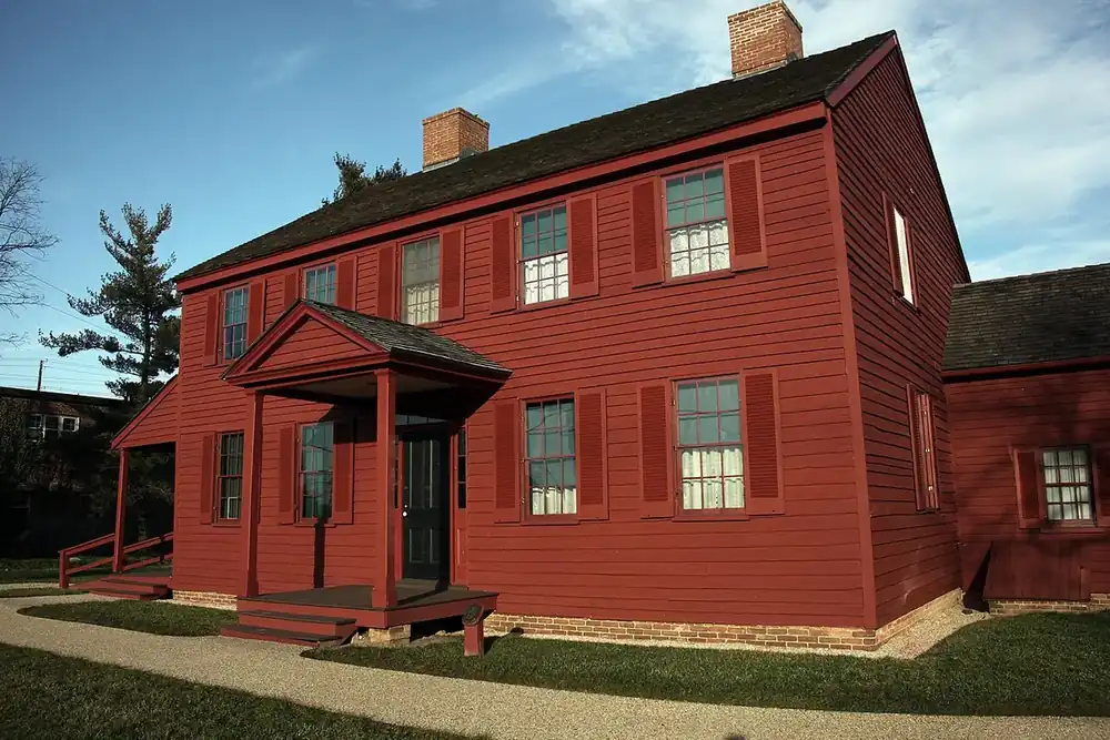 Red clapboard Surratt House, a historic house museum, under a blue sky in Clinton, Maryland