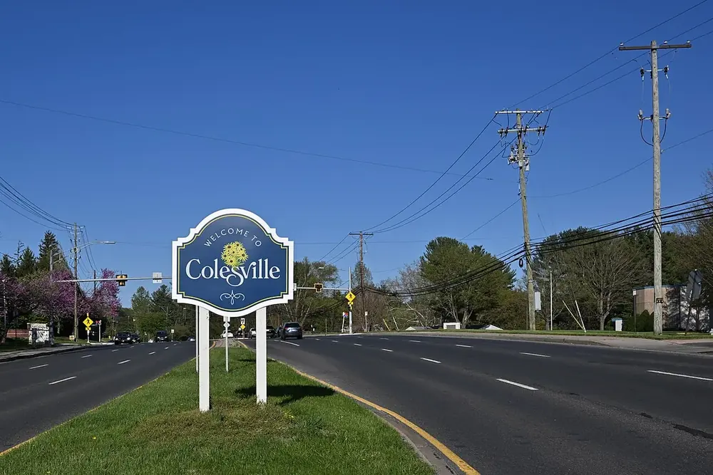 Welcome to Colesville sign on a grassy median along tree-lined Randolph Road in Colesville, Maryland
