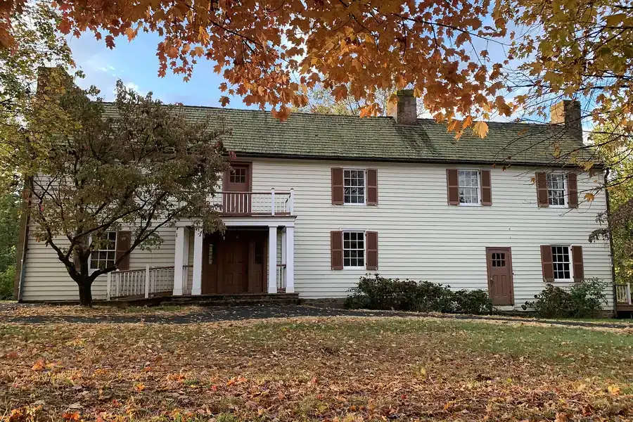 Historic white clapboard Dranesville Tavern framed by orange autumn leaves in Dranesville, Virginia