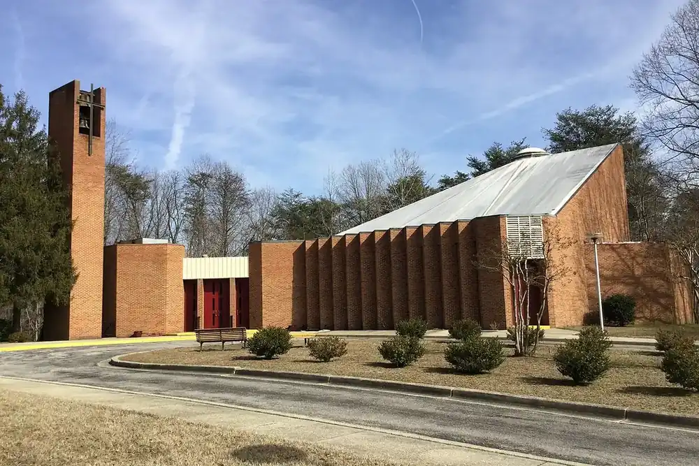 Brick Holy Spirit church with a square bell tower and lawn in Forestville, Maryland