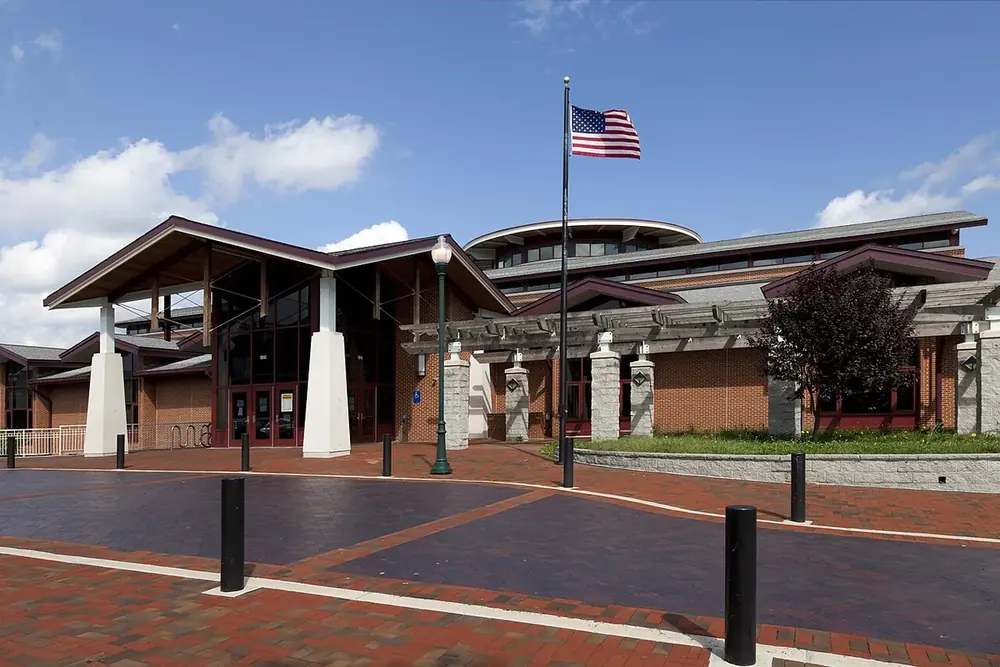 Germantown Library with a flagpole and brick plaza under a blue sky in Germantown, Maryland