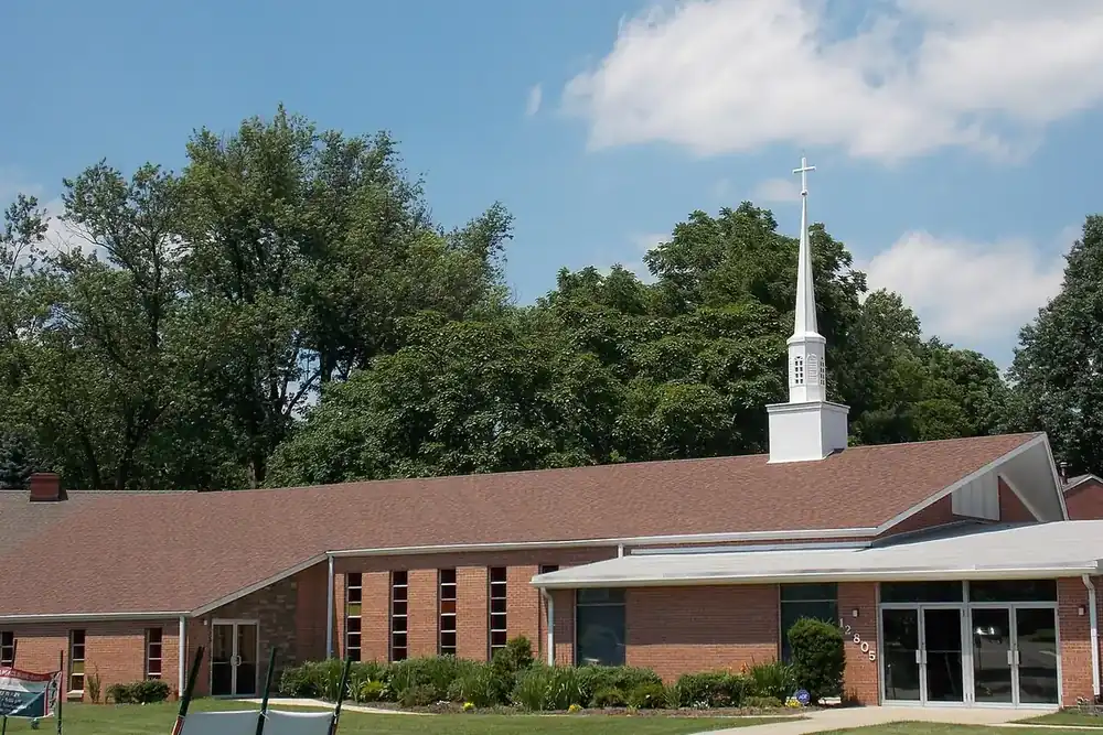 Brick church with a white steeple among tall trees in Glenmont, Maryland