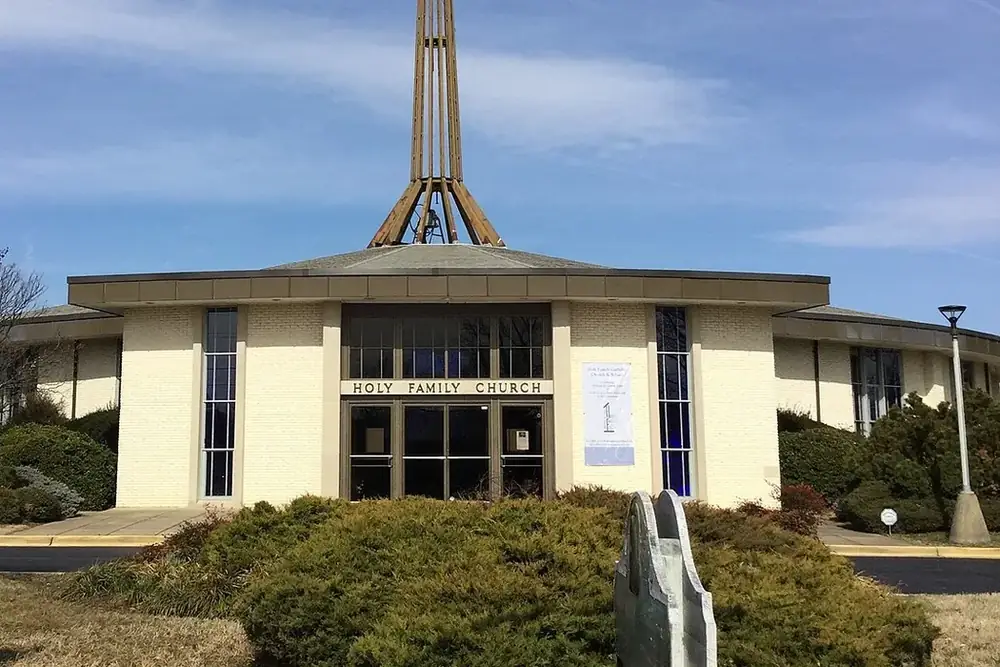Cream-colored Holy Family Church with an open metal spire in Hillcrest Heights, Maryland