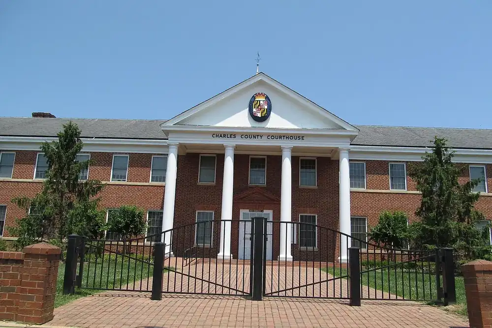 Columned brick Charles County Courthouse behind an iron gate in La Plata, Maryland