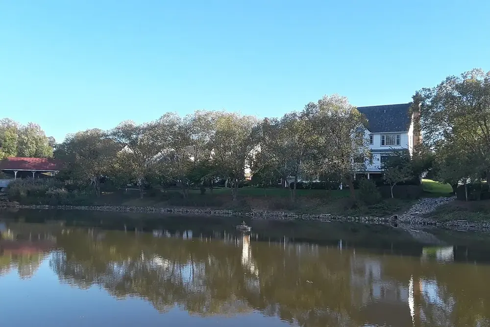 Houses and trees reflected in a calm lake in Lake Ridge, Virginia