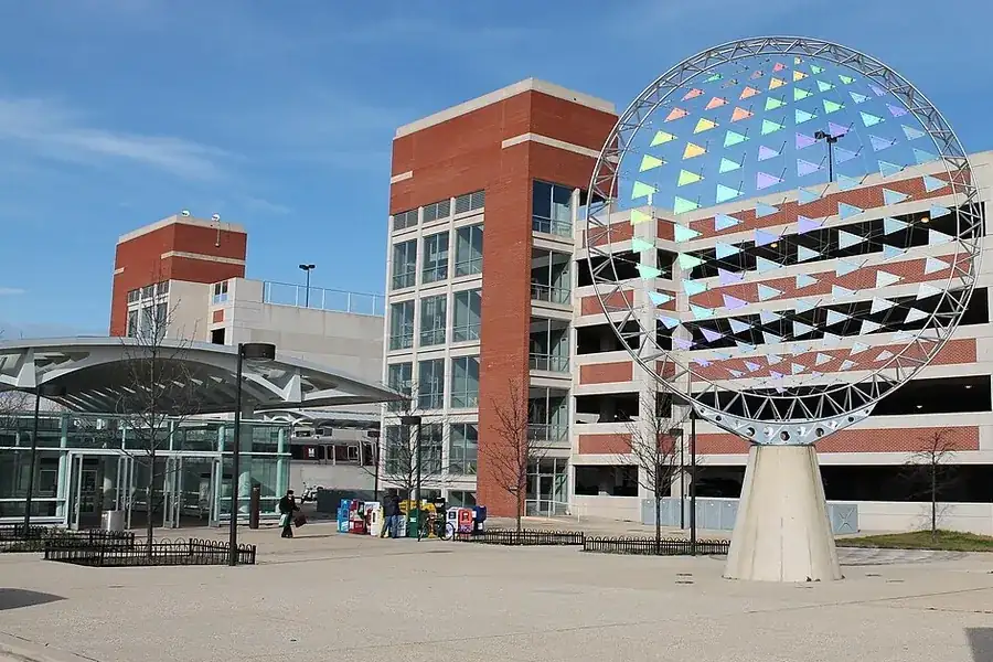 Open sphere sculpture on a sunny plaza beside brick and glass buildings in Largo, Maryland