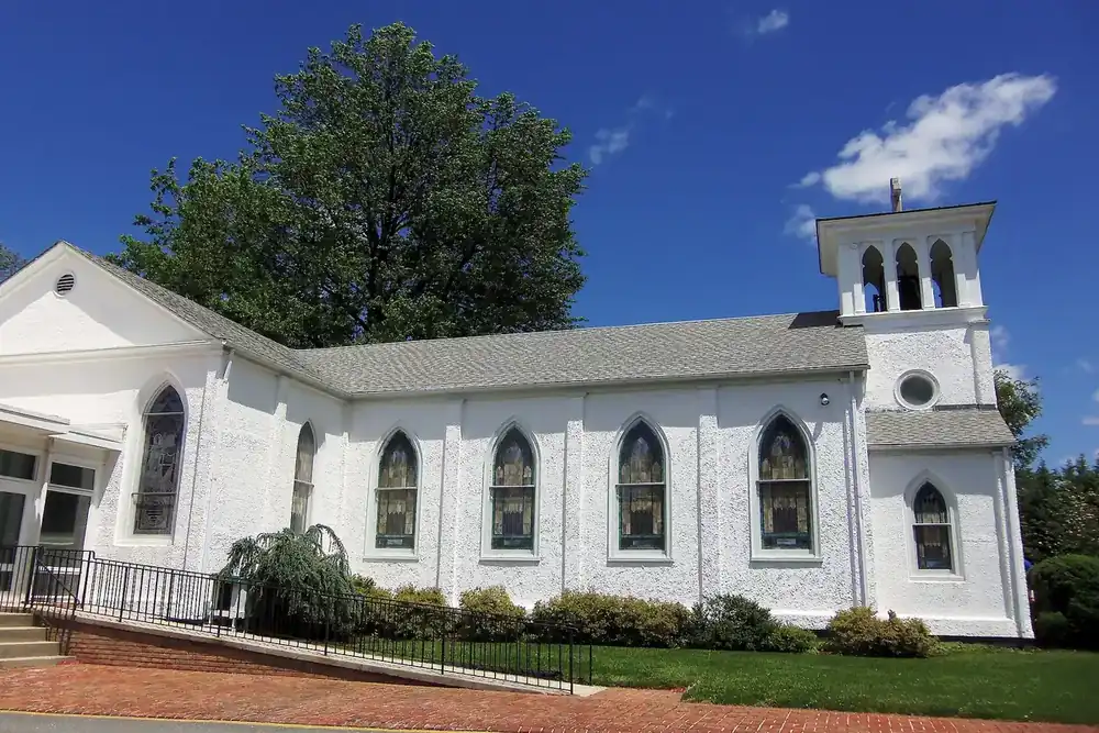 White St. John's Episcopal Church with its bell tower under a blue sky in Olney, Maryland