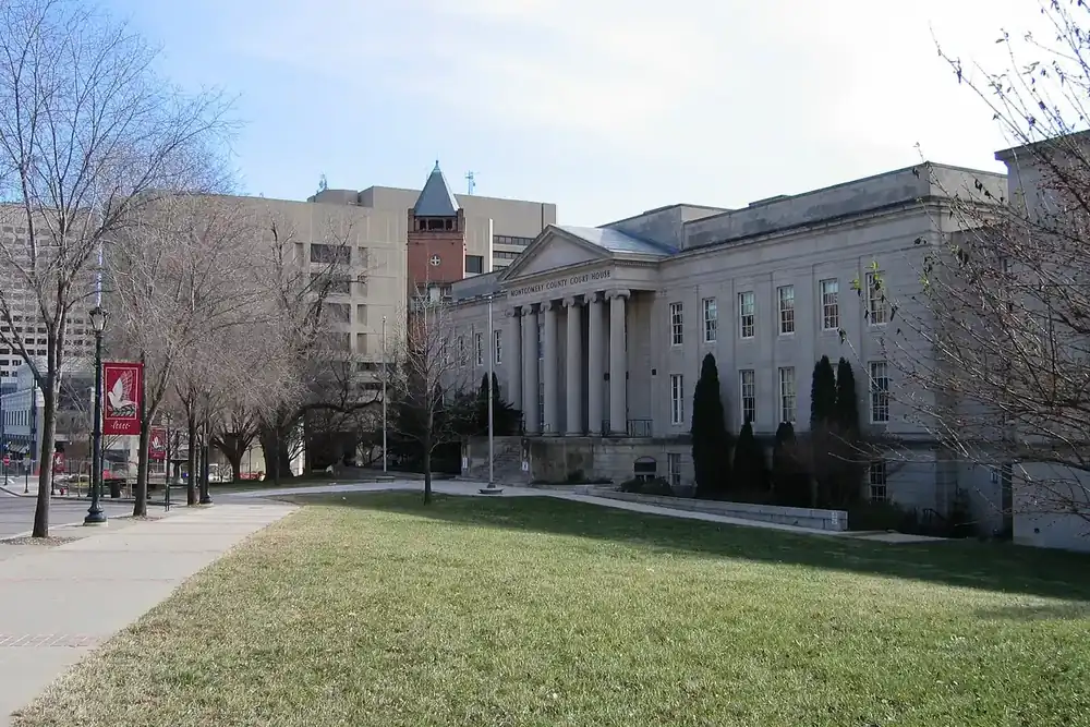 Columned Montgomery County Courthouse and red brick clock tower beside a lawn in Rockville, Maryland