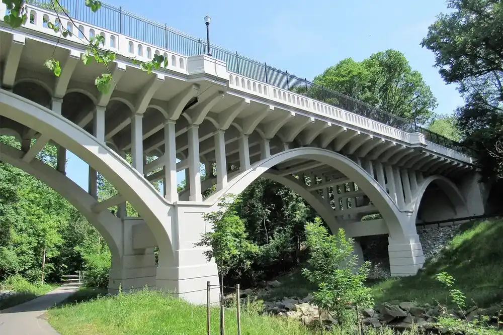 Arched concrete Carroll Avenue Bridge over a wooded trail along Sligo Creek in Takoma Park, Maryland
